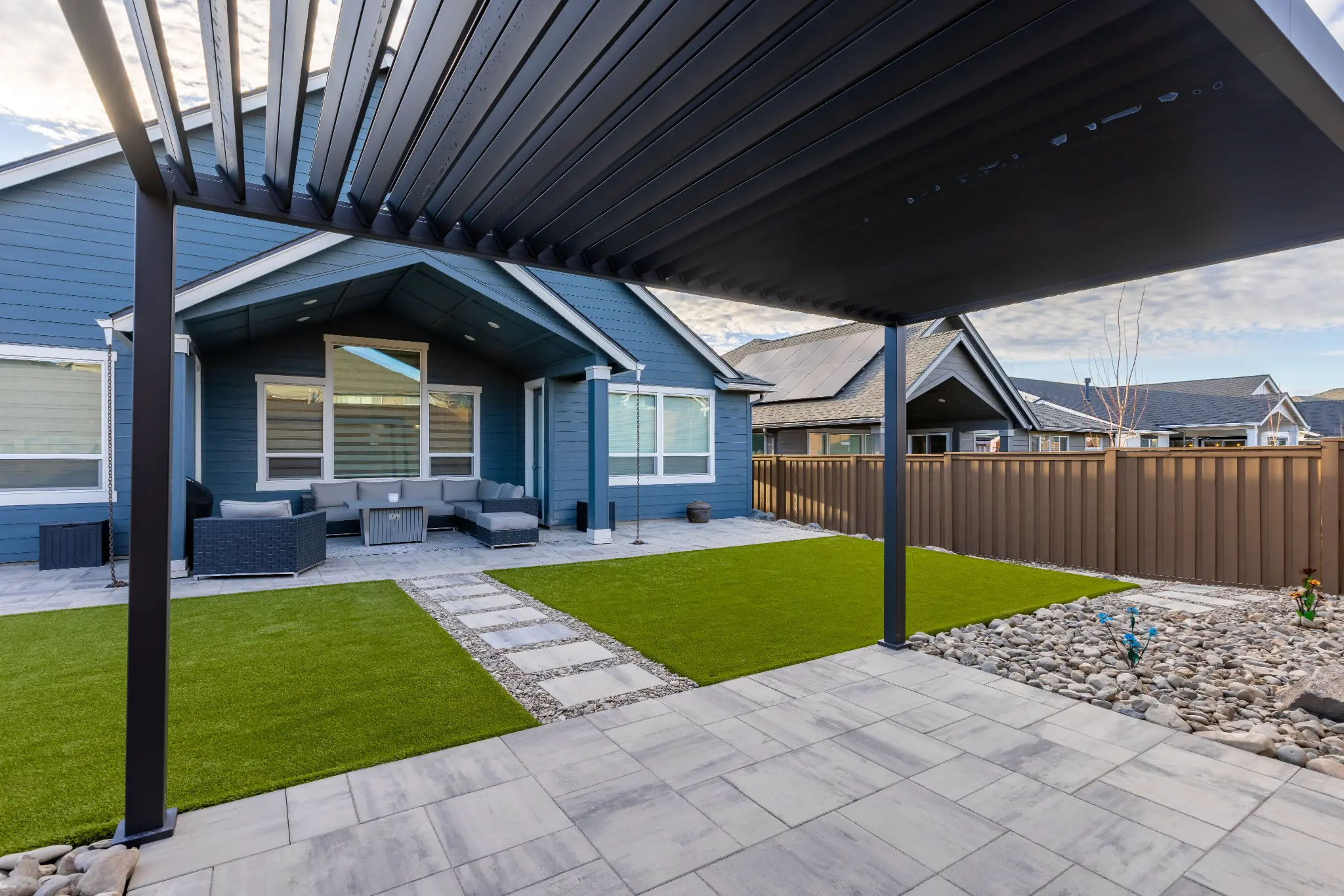Finished paver patio with louvered pergola, synthetic turf, and stone stepping path — NE Bend