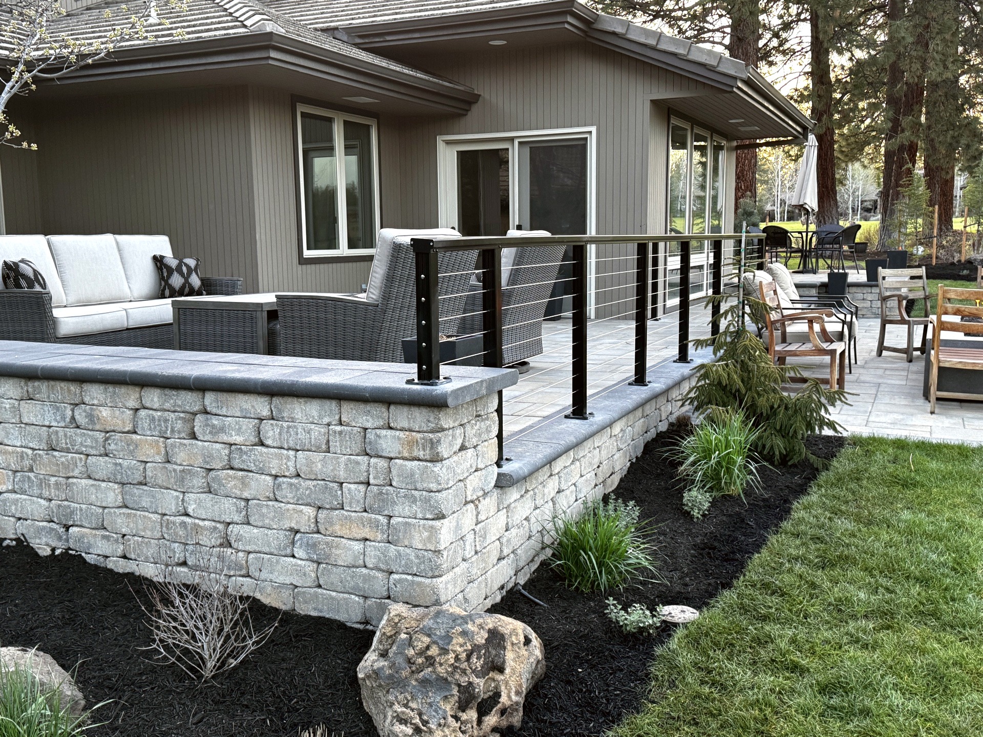 Raised paver patio with cable railing and stone retaining wall in Broken Top Bend Oregon
