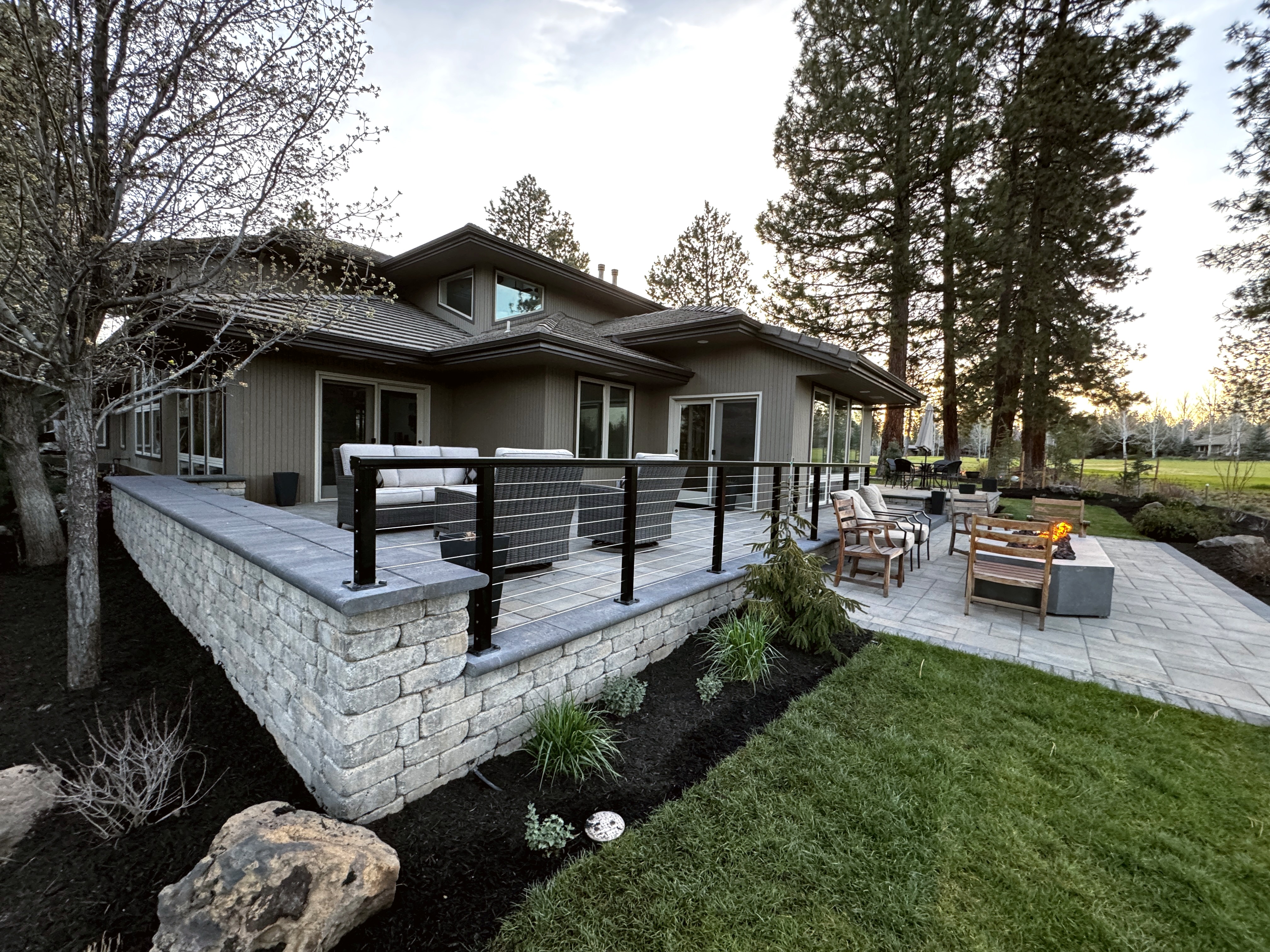 Raised Belgard paver patio with fire pit seating area at sunset in Broken Top Bend Oregon