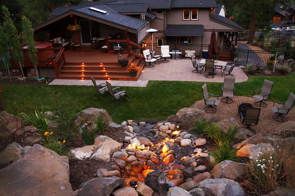 NW Bend landscape lighting illuminating water feature and trees at night — Bend, Oregon